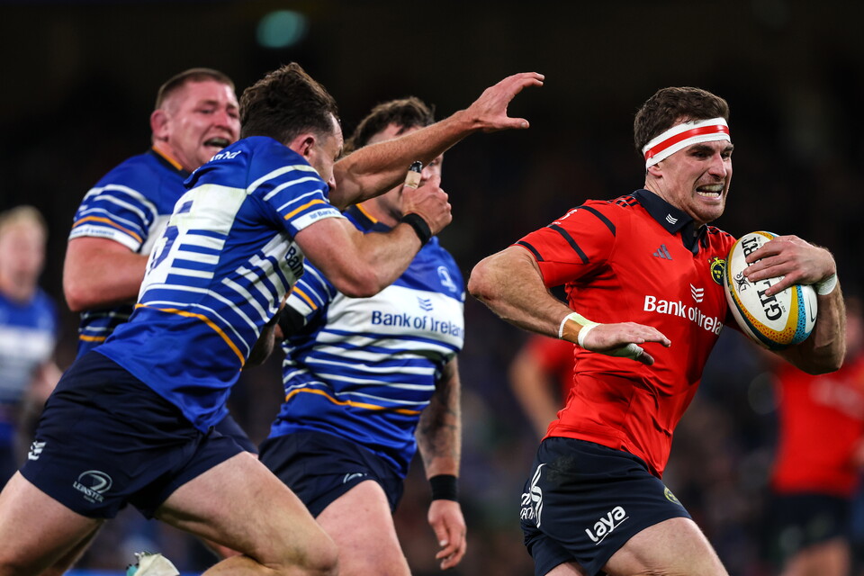 Player in red tackles opponent in blue, holding rugby ball, intense match.