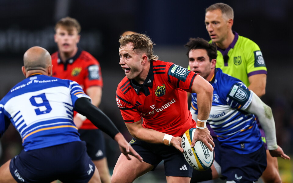 Players engage in rugby action with one player in red holding the ball.