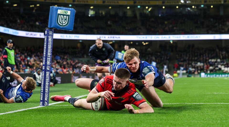 Two rugby players are tackling each other on the pitch.