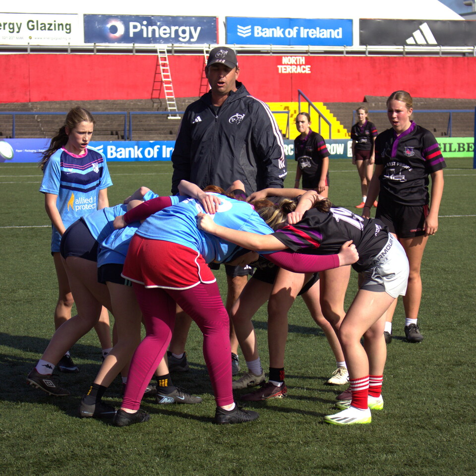 A group of women rugby players huddle together on a field.