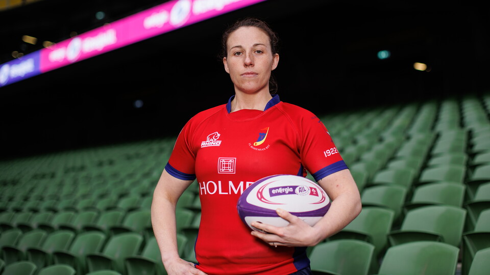 Woman in red rugby shirt holding rugby ball in stadium
