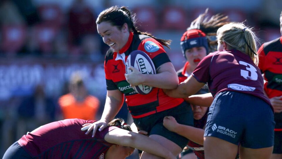 A player in maroon and black tackles another player in a maroon jersey during a rugby game.