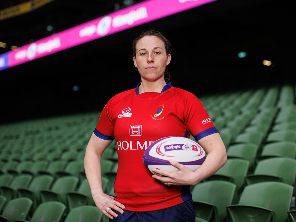 Woman in red rugby shirt holding rugby ball in stadium