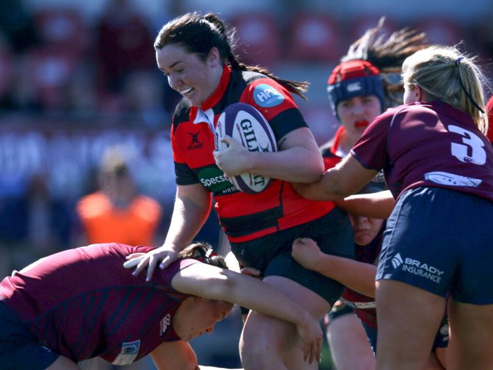 A player in maroon and black tackles another player in a maroon jersey during a rugby game.